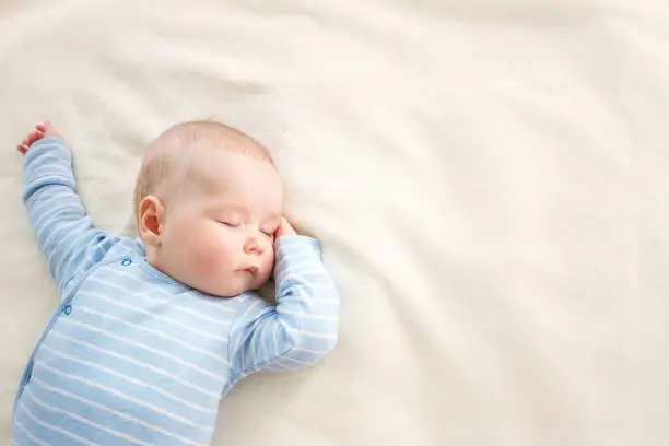 little boy sleeping on soft white blanket