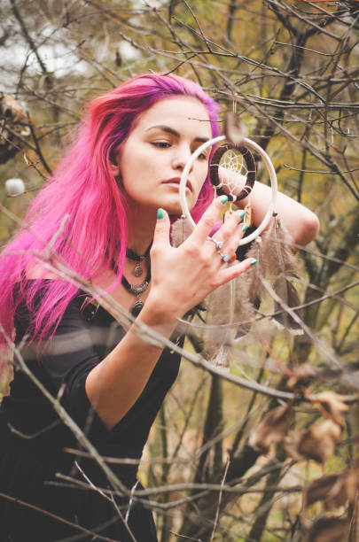 istock Young witch in black dress is making magic witchcraft in the forest with a dreamcatcher 937849576