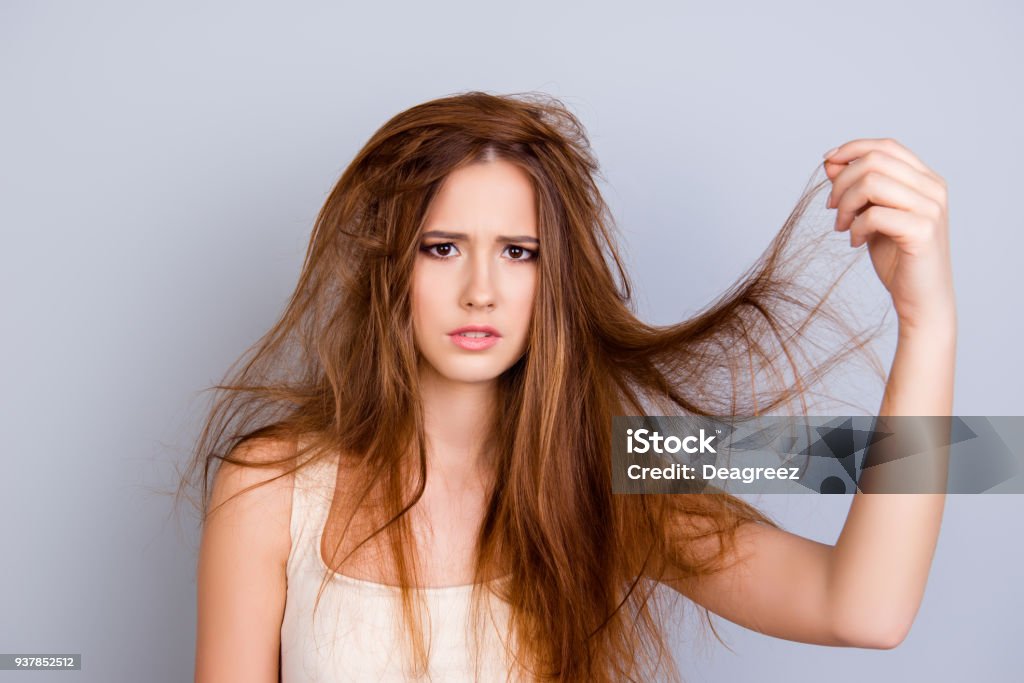 Retrato de joven frustrada con el pelo sucio en el fondo puro, con camiseta casual blanco, con su pelo de cerca - Foto de stock de Pelo libre de derechos