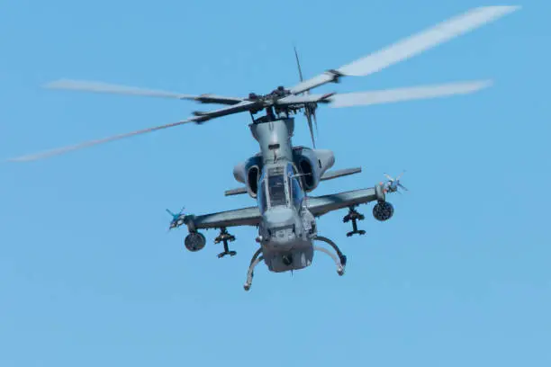 Very close frontal view of an AH-1 Cobra attack helicopter against the sky, with missiles, rockets and machine gun