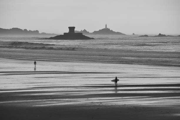 Telephoto B&W image of a surfing beach.