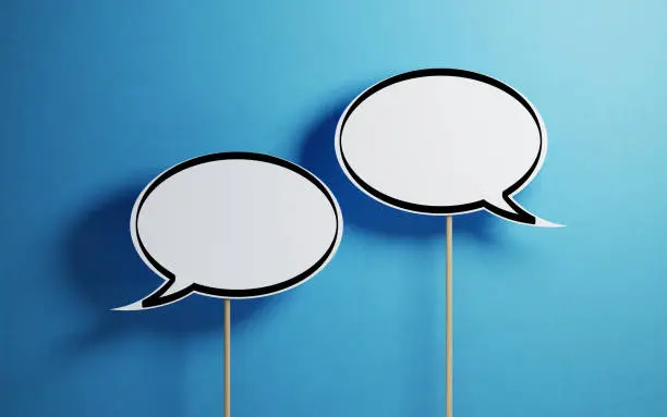 Photo of White Chat Bubbles With Wooden Sticks On Blue Background