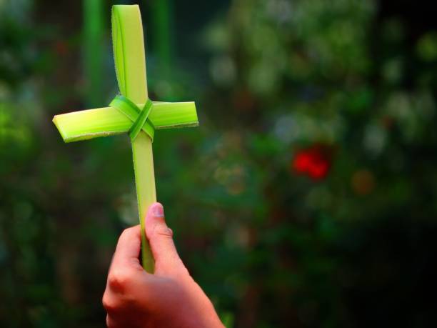 General Villamil Playas, Guayas, Ecuador - April 10, 2022: Catholic priest sprinkling holy water on parishioners holding palm leaves during a vibrant Palm Sunday mass in General Villamil Playas, Ecuador, celebrating faith and community