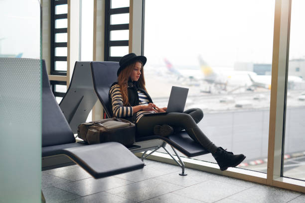 istock Tired young woman using a laptop in an airport 937871382