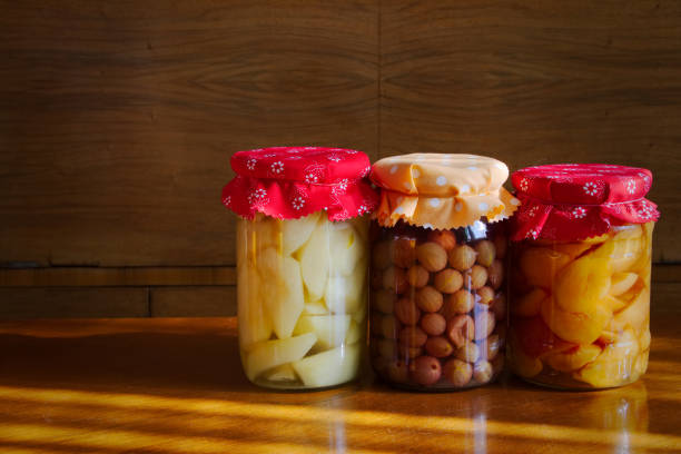 conserved fruit in glass on wooden table, stored homegrown peaches, pears and gooseberries, organic food