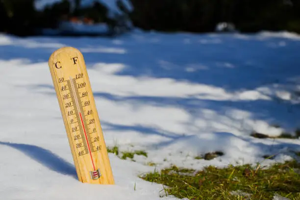 Photo of thermometer in melting snow, spring is coming
