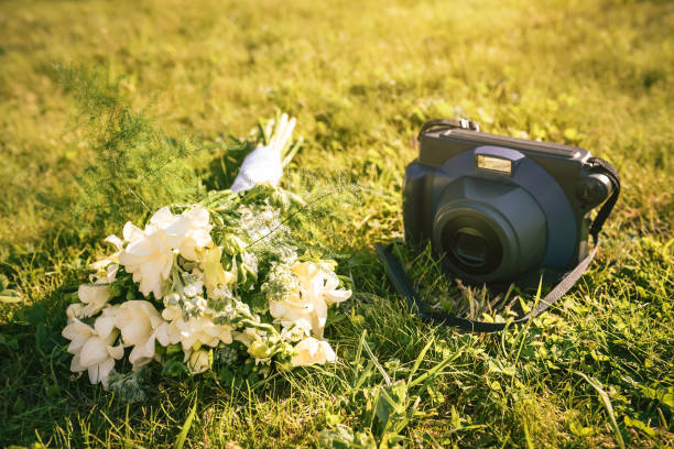 Retro camera and wedding bouquet on green grass. Moment photo for celebration