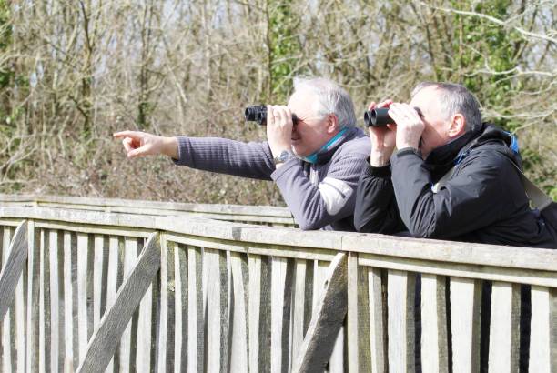 istock Two men resting on fence observing birds with binoculars. 937885246