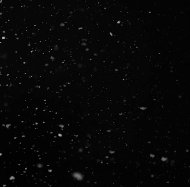 istock Particles of snow on a black background 937887684