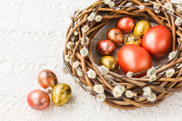 istock Easter willow wreath and colorful  Easter eggs on white tablecloth. Top view, copy space 937894538
