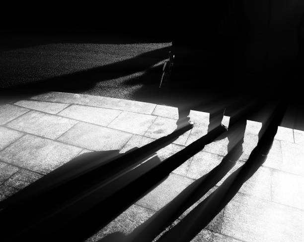 istock Back and white shadows of people with dramatic rays background 937895092