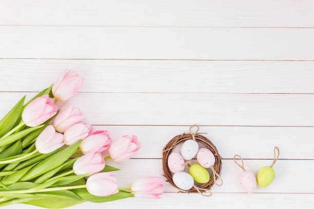 istock Tulips and decorative Easter eggs in small nest on white table. Top view, copy space 937898656