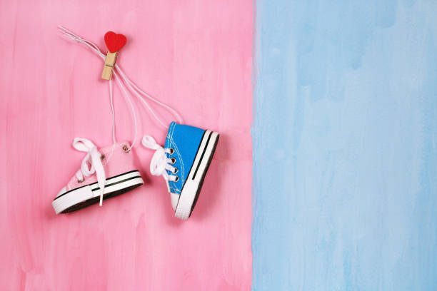 Baby sneakers on pink and blue background, boy or girl concept stock photo