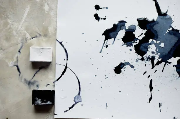 A palette of black and white paint. a sheet of white art paper with black dye ink.