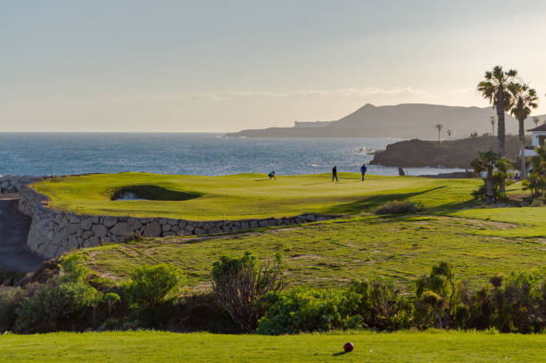 jogadores de golfe em um verde de frente para o oceano atlântico na ilha de tenerife na espanha - golf golf swing sunset golf course - fotografias e filmes do acervo