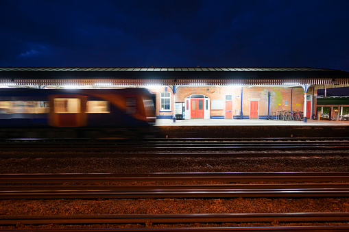 Commuter train departing a UK station at night