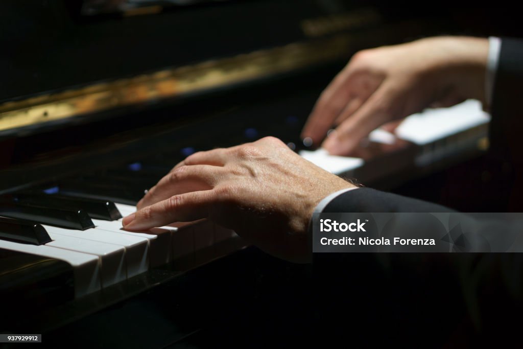 Professional musician pianist hands on piano keys of a classic piano in the dark. Piano Stock Photo