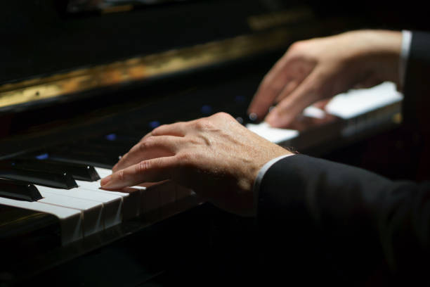 professional musician pianist hands on piano keys of a classic piano in the dark. - piano imagens e fotografias de stock