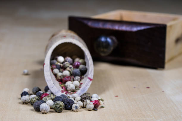 A grain of pepper on a kitchen table. Ground pepper in a kitchen mill. Culinary spices on a light background.