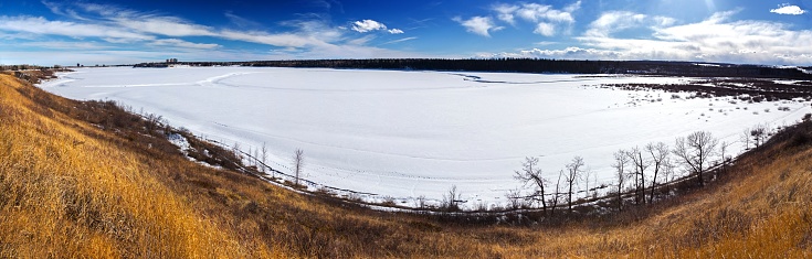 Scenic Wide Panoramic Landscape View of Snowy Frozen Glenmore Reservoir, Natural Prairies Grassland and Rocky Mountains Foothills in South Calgary Alberta Canada