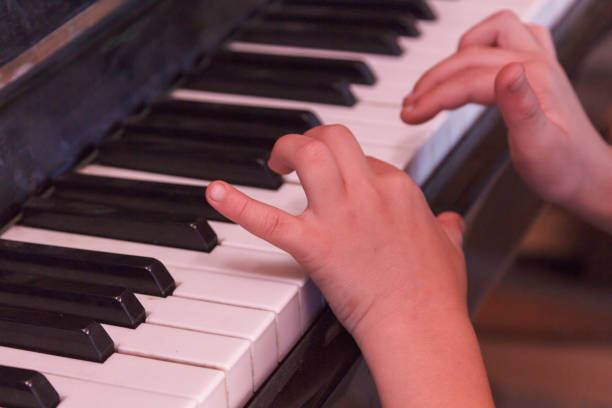 istock Child plays old piano with hands. 937942272