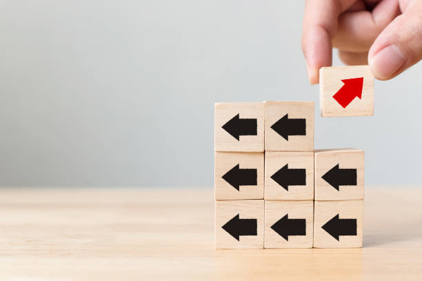 istock Hand picked wooden block with red arrow facing the opposite direction black arrows, Unique, think different, individual and standing out from the crowd concept 937973076