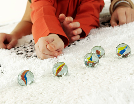 Small kids playing with marbles on carpet