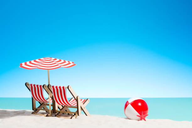 istock Two lounge chairs with parasol and beach ball on the coast 937975928
