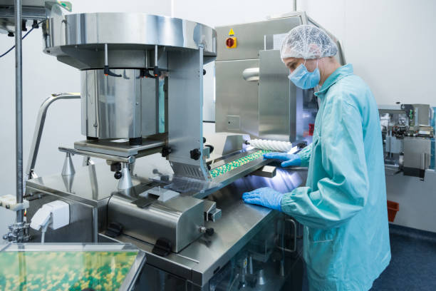 istock Pharmaceutical industry man worker in protective clothing operating production of tablets in sterile working conditions 937976270
