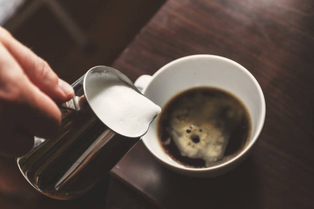 istock man pouring into a cup of coffee with milk 937976544