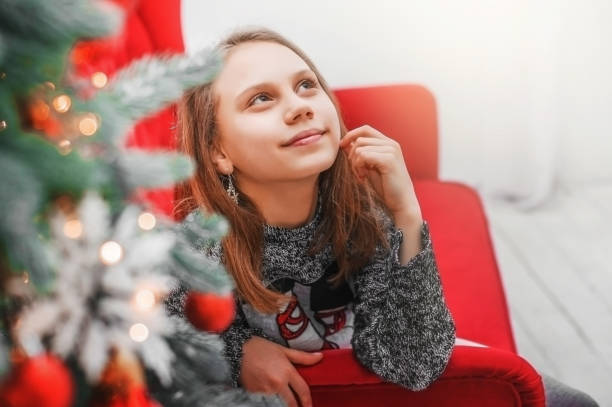 istock Child  girl on the couch next to Christmas tree. 937976922