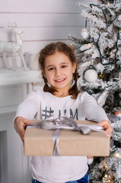 istock Cute child girll with a gift near the Christmas tree 937977076