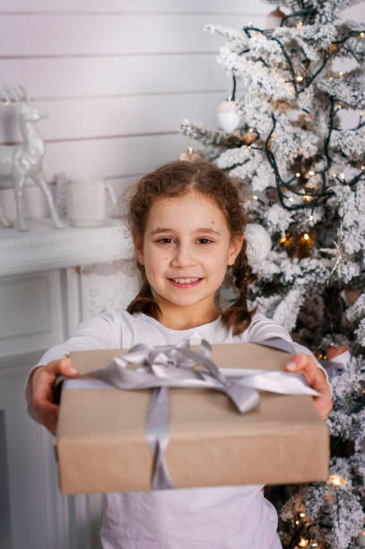 istock Cute child girll with a gift near the Christmas tree 937977078