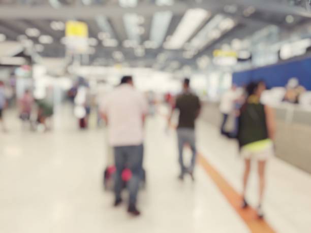 istock Abstract blurred image background of group people or arriving passengers with their suitcases holding luggage walking in international  airport terminal, travelling or business concept. vintage tone. 938016900