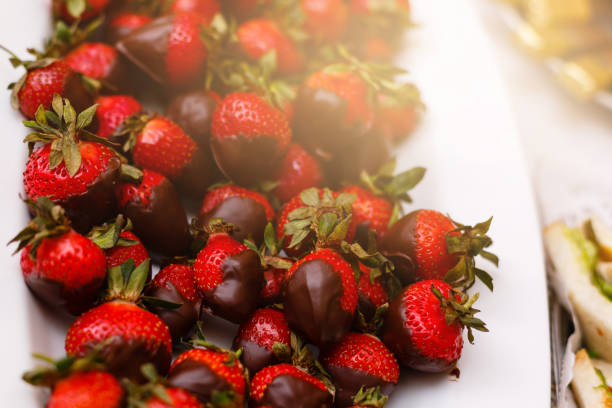 istock Fresh strawberries dipped in dark chocolate on blue wooden background 938027340