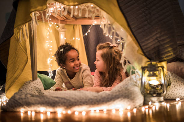 istock Little girls communicating while relaxing in a tent at home. 938027358