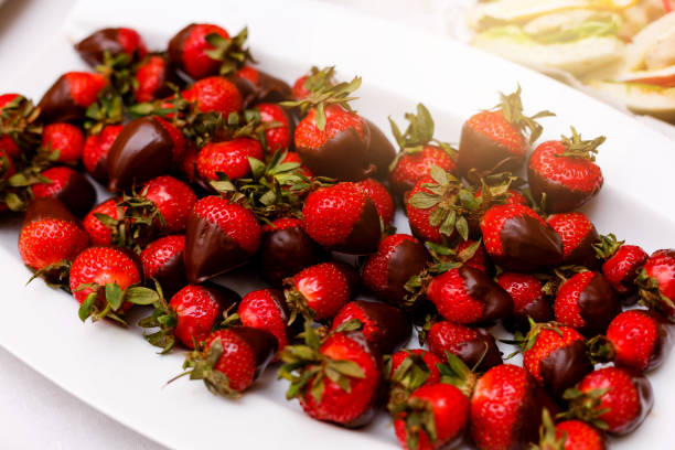 istock Fresh strawberries dipped in dark chocolate on blue wooden background 938027378