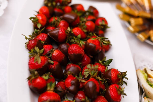 istock Fresh strawberries dipped in dark chocolate on blue wooden background 938027410