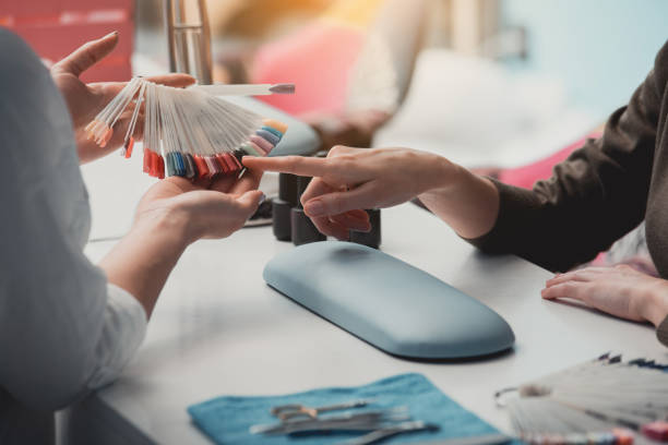 Woman arm demonstrating color for manicure This is one. Close up female hand pointing finger on nail polish testers in beauty salon fake nails for kids stock pictures, royalty-free photos & images
