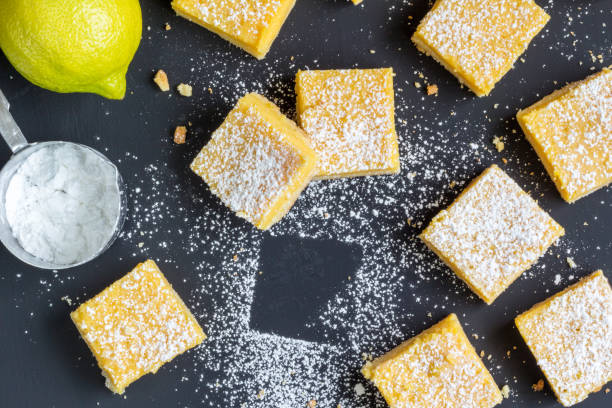 istock Lemon squares on black table with lemon, icing sugar - Top view photo 938031916
