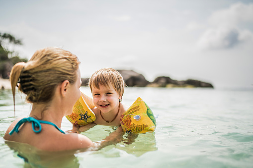 Happy mother and son having fun while swimming in the sea.