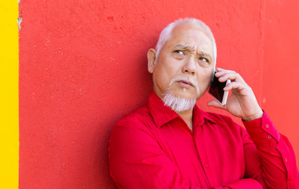 istock Mature asian man on a colorful background uses a smartphone 938041022