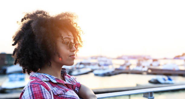 istock African woman looking at yachts on harbor 938041124