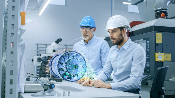 istock In High Tech Factory Two Engineers Works with Holographic Projection 3D Model of the Engine Turbine Prototype. Futuristic Desing of Virtual Mixed Reality Application. 938057516