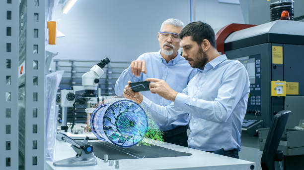 Two Engineers Works with Mobile Phone Using Augmented Reality Holographic Projection 3D Model of the Engine Turbine Prototype. Development of Virtual Mixed Reality Application. Two Engineers Works with Mobile Phone Using Augmented Reality Holographic Projection 3D Model of the Engine Turbine Prototype. Development of Virtual Mixed Reality Application. hologram photos stock pictures, royalty-free photos & images