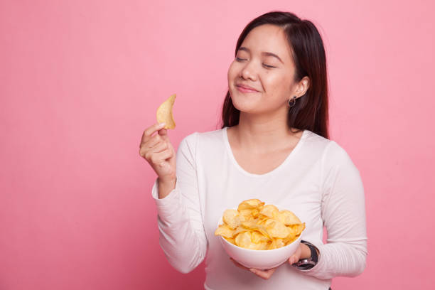 istock Young Asian woman eat potato chips. 938057602