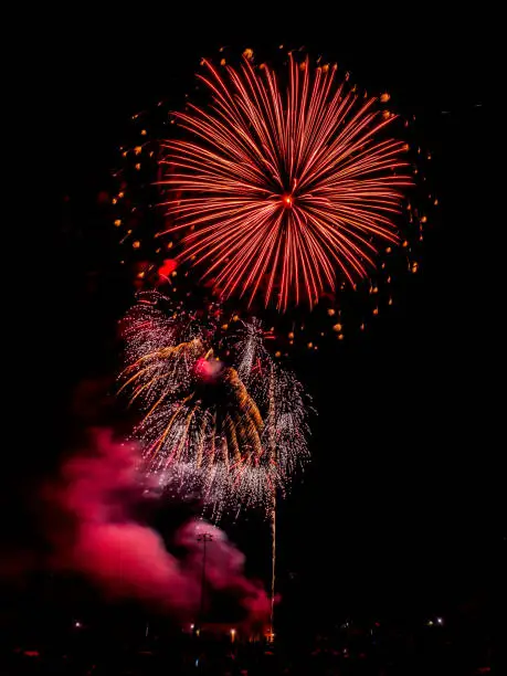 Independence day fourth of July real fireworks display exploding in the sky with vivid colors in a black night sky with smoke billowing below