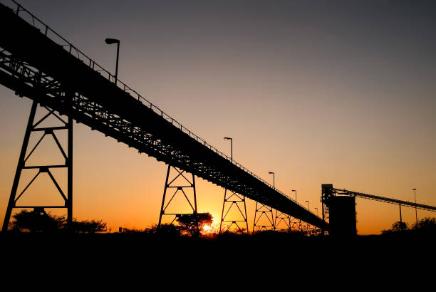 Silhouette of mining silo and conveyor belts at sunset