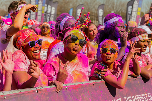 Johannesburg, South Africa,  May 21, 2017, Young people having fun at The Color Run 5km Marathon\nBright color paint all over a crowd of young people at the Color Run in Johannesburg South Africa. Named \