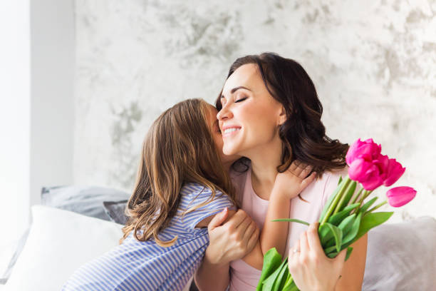 young woman embrace with small girl - mothers day flower gift bouquet imagens e fotografias de stock